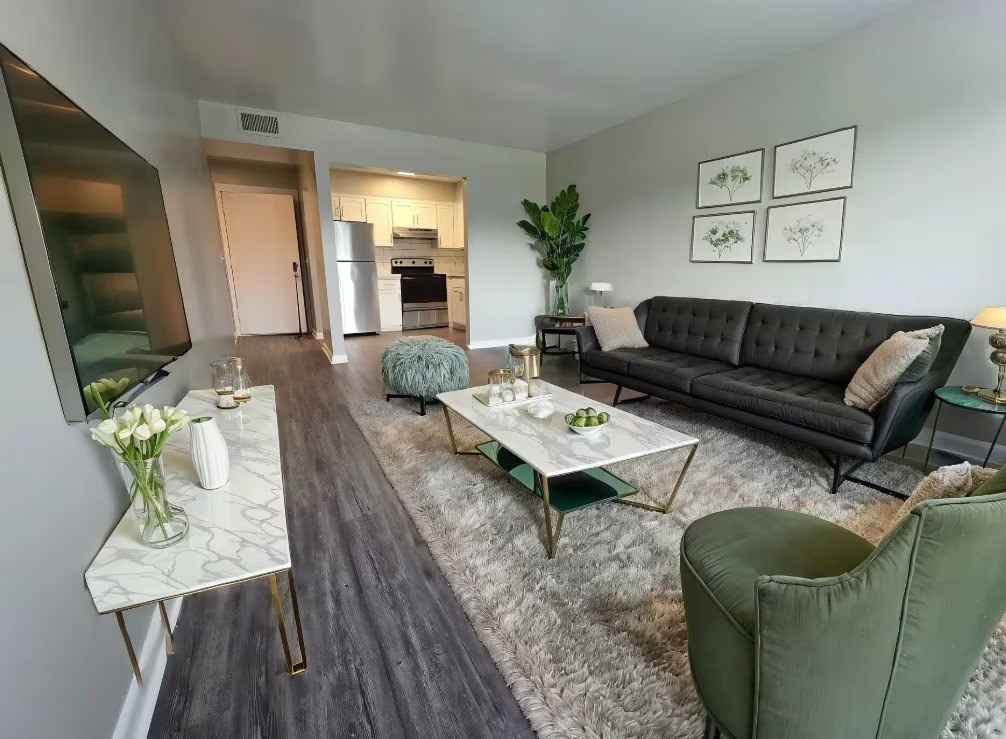 A living room with a black couch, a white coffee table, and a green armchair.