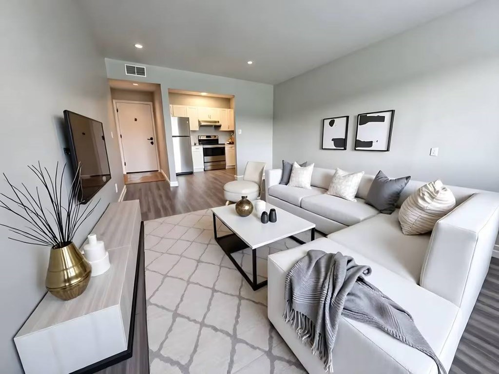 A modern living room with a white couch and a television on the left side.