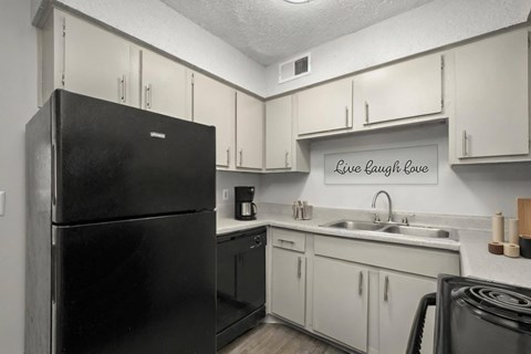 A black refrigerator in a kitchen with a sign that says Live Laugh Love.