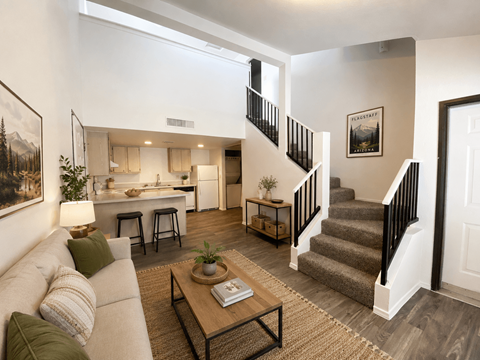 A living room with a couch, a coffee table, and a staircase.
