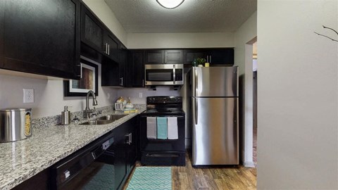 A kitchen with black cabinets and a stainless steel refrigerator.