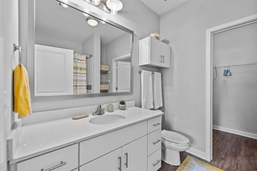 A bathroom with a white counter top and a white toilet.