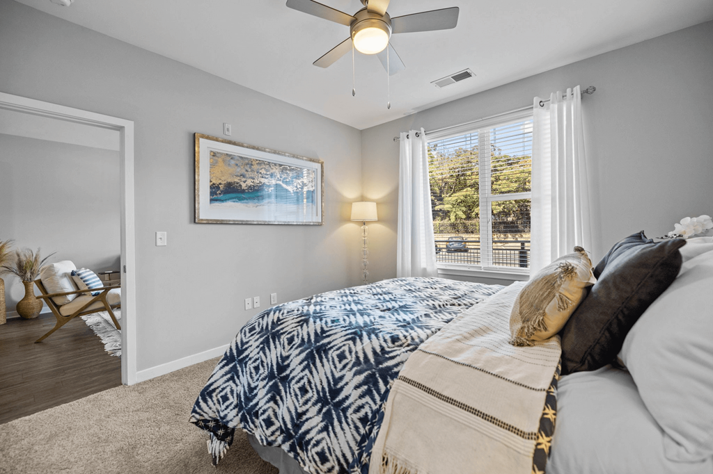 A bedroom with a bed covered in a blue and white patterned comforter.