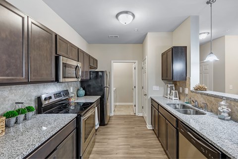 A kitchen with dark brown cabinets and granite countertops.