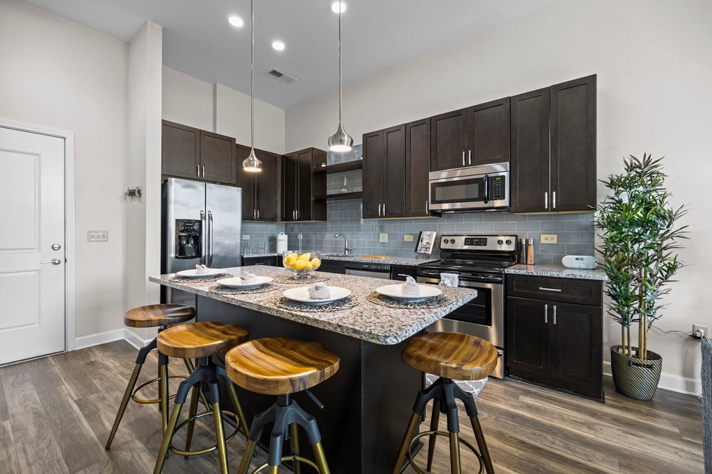 A kitchen with a black countertop and bar stools.