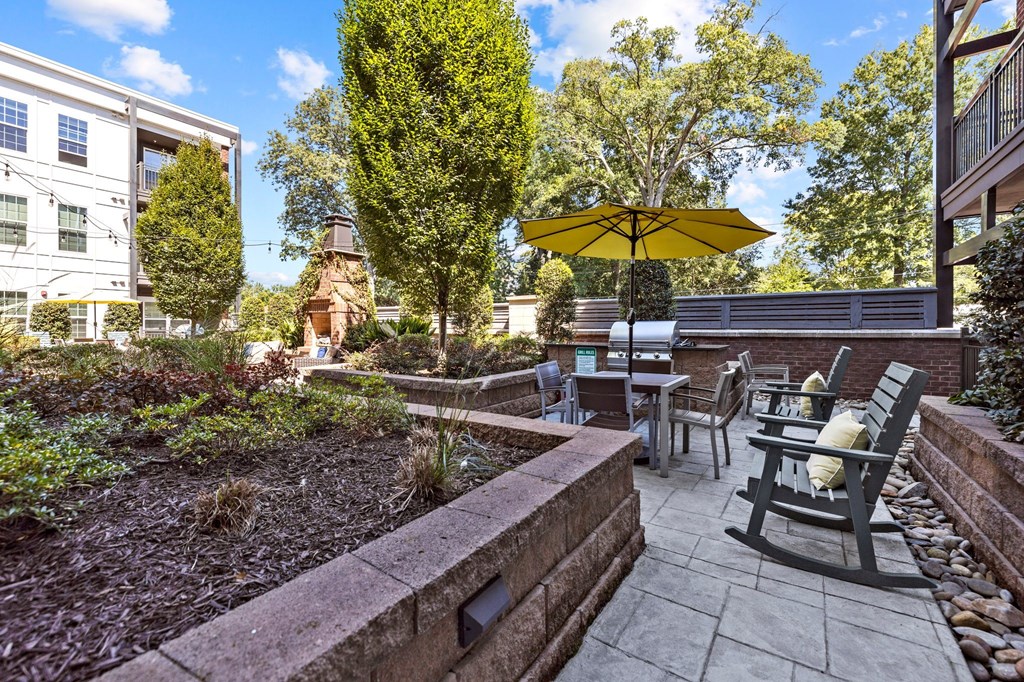 A patio with a yellow umbrella and chairs.