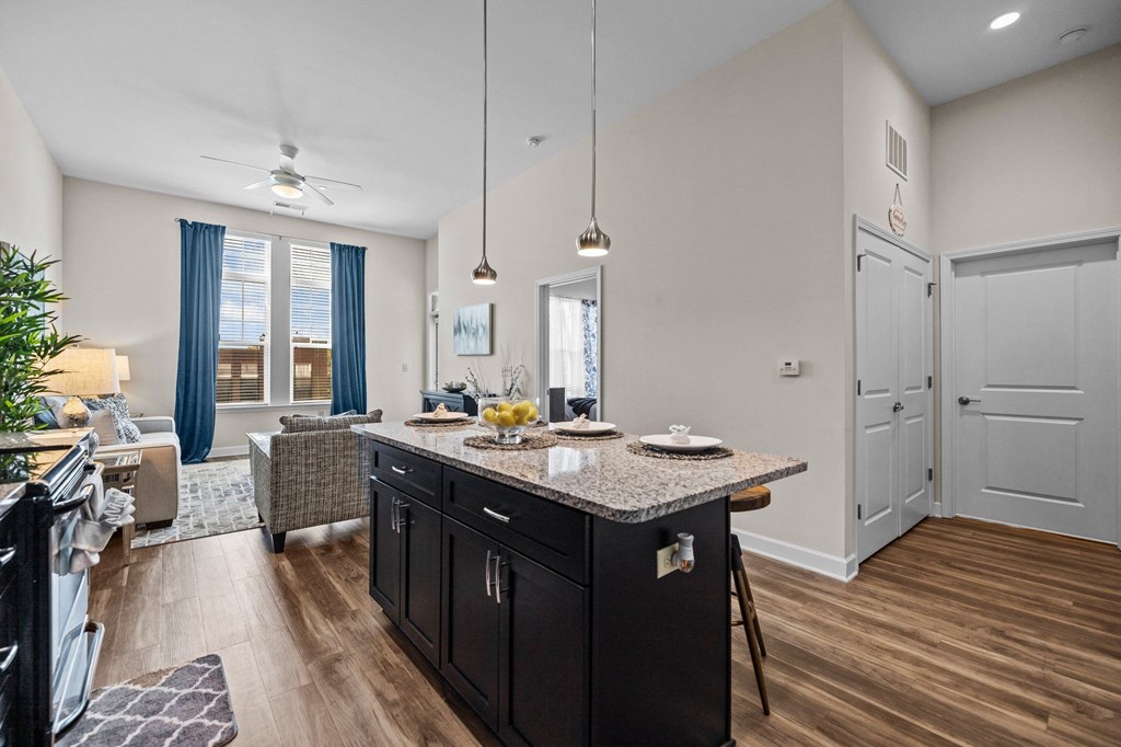 A kitchen with a black counter top and wooden floors.