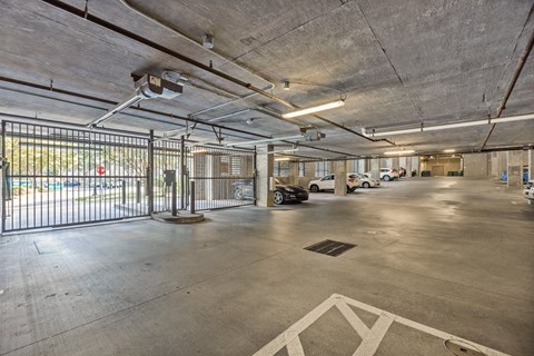 A parking garage with a black gate and a white arrow on the ground.