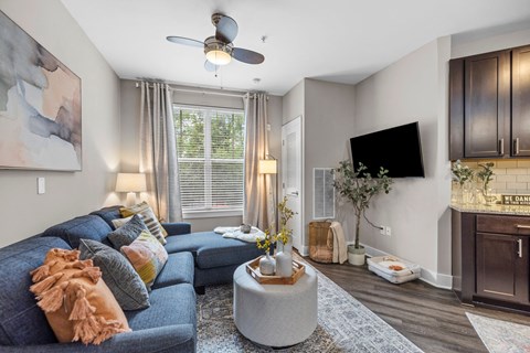 A living room with a blue couch and a ceiling fan.