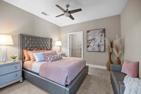 A bedroom with a bed, nightstand, and a ceiling fan.