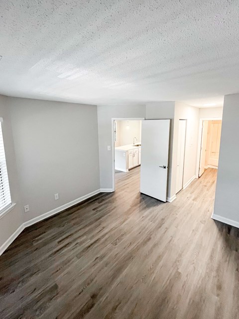 A room with a white door and wooden flooring.