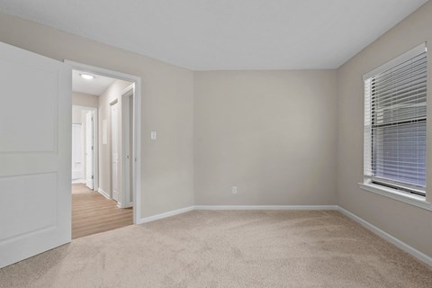 A room with a white door and carpeted floor.