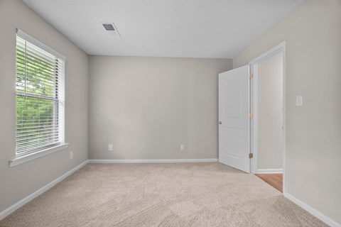 A room with a carpeted floor and a white door.