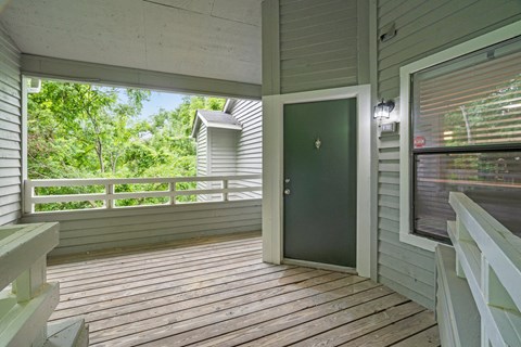 A green door is on the right side of a wooden porch.