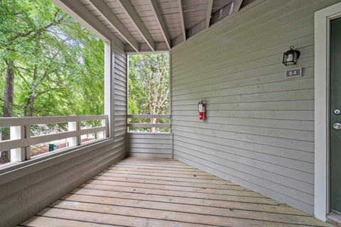 A wooden deck with a door and a fire extinguisher on the wall.