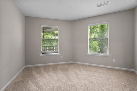 A room with two windows and carpeted floor.