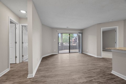 A spacious room with wood flooring and white walls.