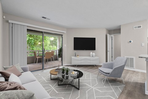 A modern living room with a grey sofa, a white coffee table, and a flat-screen TV mounted on the wall.