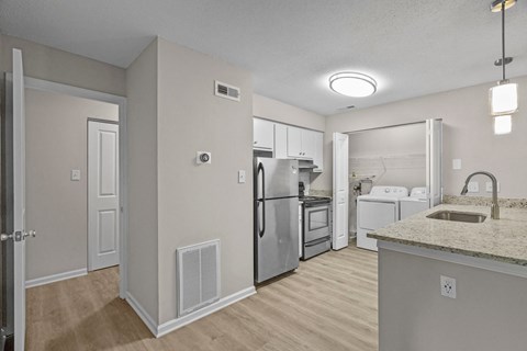 A kitchen with a refrigerator, sink, and oven.