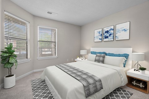 A bedroom with a large bed and a potted plant.