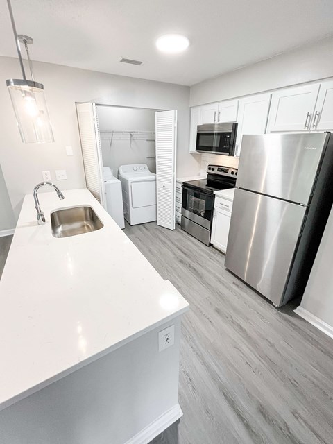 A modern kitchen with a white countertop and stainless steel appliances.