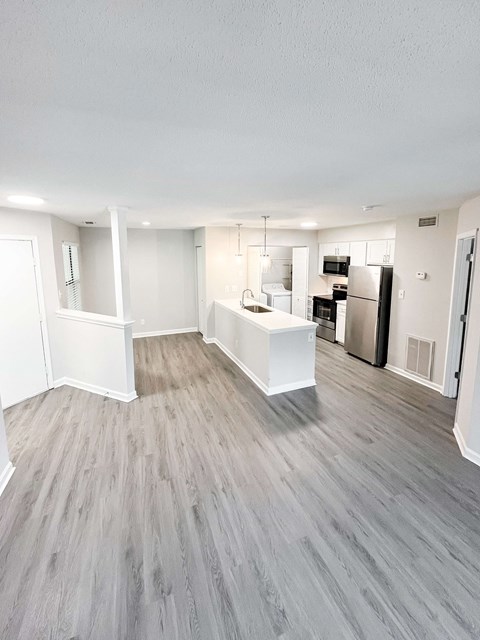 A kitchen with a refrigerator, sink, and cabinets.