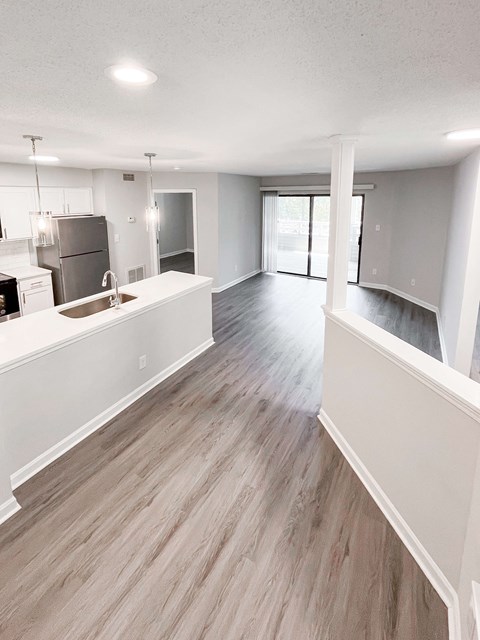 A spacious kitchen with white cabinets and a wooden floor.