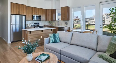 A modern kitchen with wooden cabinets and a grey sofa.
