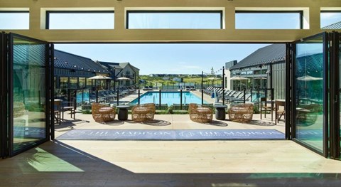 A view of a pool area with chairs and a building in the background.
