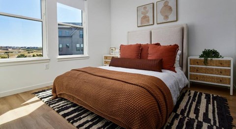 A bedroom with a large bed and a view of the outdoors through a window.