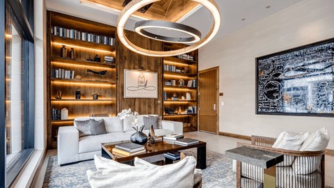 A modern living room with a large painting on the wall and a bookshelf filled with books.
