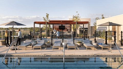 A poolside area with people relaxing and a building in the background.