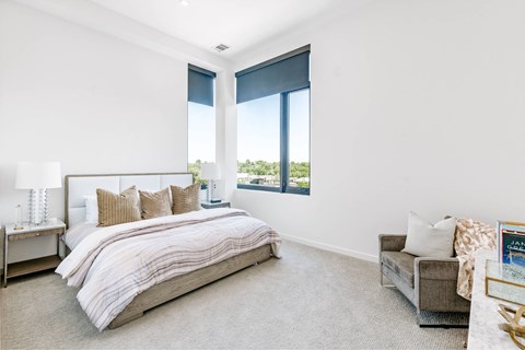 A bedroom with a large bed and a window with blinds.