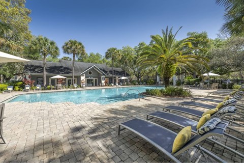 A pool area with sun loungers and a building in the background.