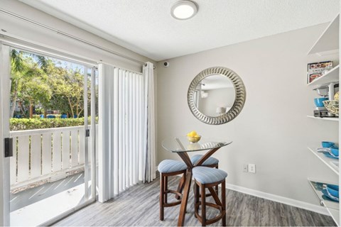 A dining area with a table and chairs and a mirror on the wall.
