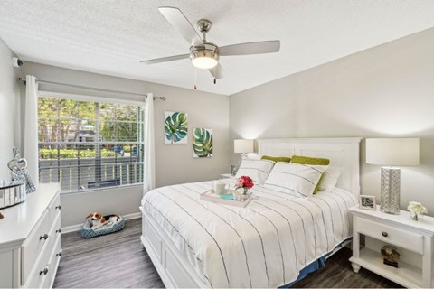 A bedroom with a bed, nightstand, and a fan.