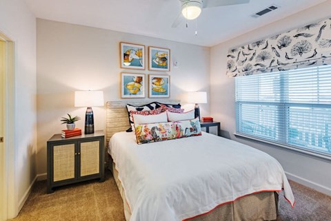 A bedroom with a bed, nightstand, and pictures on the wall.