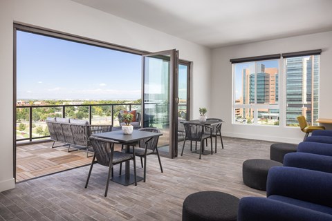 A modern dining room with a view of the cityscape outside the large windows.