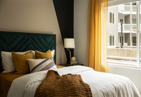 A bedroom with a large bed and a window overlooking a balcony.