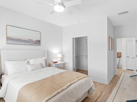 A bedroom with a large bed and a painting on the wall.