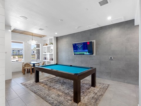 A pool table in a room with a television mounted on the wall.