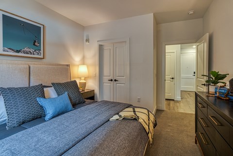 A bedroom with a large bed and a painting of a ski lift on the wall.
