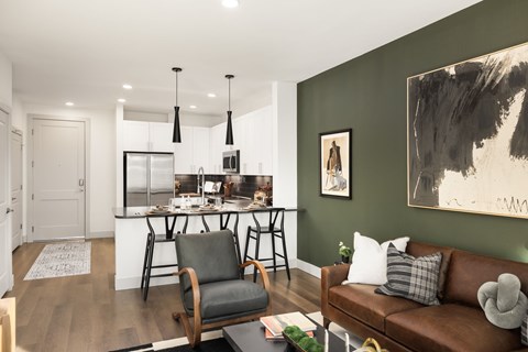 A modern living room with a brown leather couch and a kitchen area in the background.