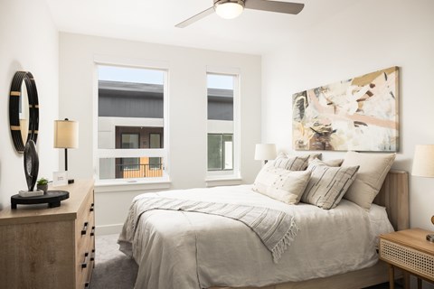 A bedroom with a bed, a nightstand, and a window.