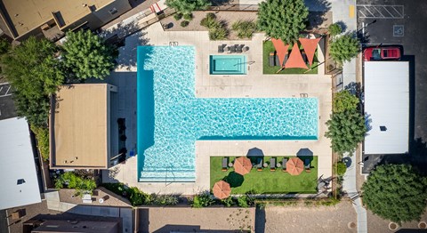 An aerial view of a pool surrounded by trees and a building.