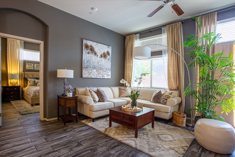 A living room with a white couch and a painting on the wall.