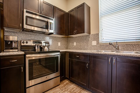 A kitchen with dark wood cabinets and stainless steel appliances.