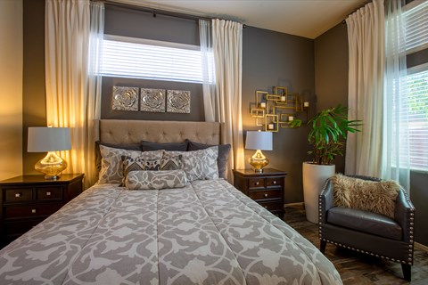 A bedroom with a large bed and a chair.