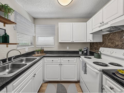 A kitchen with white cabinets and a black countertop.