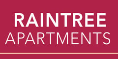 A sign that says "Raintree Apartments" on a red background.
